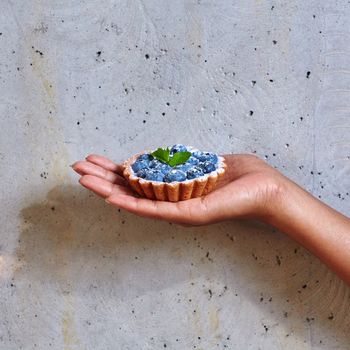 Dessert in a hand on a concrete background with copy space
