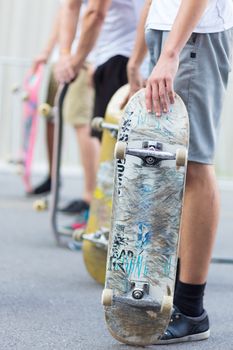 Young skateboarders skateboarding on the street. Group of friends standing in a row with skateboards in their hands. Urban life. Youth subculture.