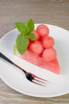 piece of watermelon with watermelon balls and mint on a plate