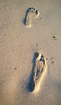 Photo representing human footprints on sand.