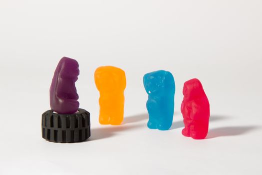 A yellow, blue and red jelly baby worship the grand oracle purple jelly baby.