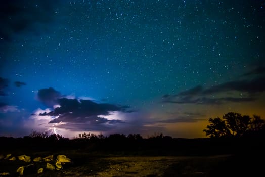 Long exposure of the stars with a burst of lightning from a small thunderstorm