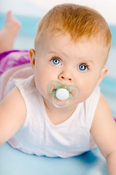 Beautiful blue-eyed baby with a pacifier. Close-up. Studio photo