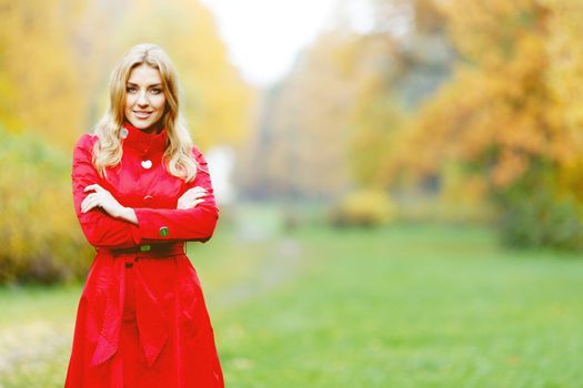 Young woman in red coat walking in autumn park