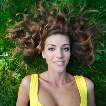 beautiful young woman in yellow dress lying on grass