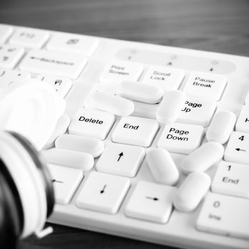 pills on keyboard computer on wooden background concept technology addiction black and white color tone style