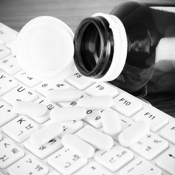 pills on keyboard computer on wooden background concept technology addiction black and white color tone style