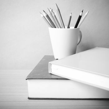 stack of book with color pencil on wood table background black and white color tone style