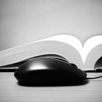 book and computer mouse on wood background black and white color tone style