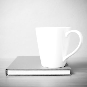 book and coffee mug on wood background black and white tone style