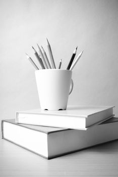 stack of book with color pencil on wood table background black and white color tone style