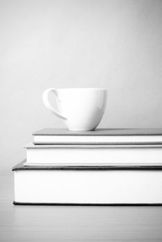 stack of book with coffee cup on wood table background black and white color tone style