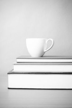 stack of book with coffee cup on wood table background black and white color tone style