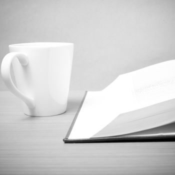 book and coffee mug on wood background black and white tone style