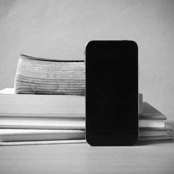 stack of book and smart phone on wood background black and white color tone style