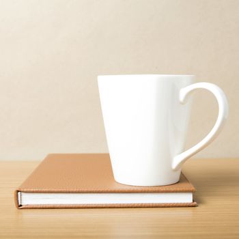 book and coffee mug on wood background