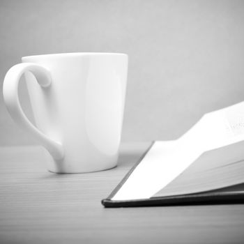 book and coffee mug on wood background black and white tone style