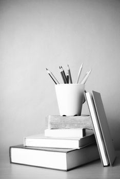 stack of book with color pencil on wood table background black and white color tone style