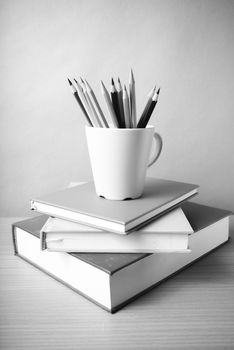 stack of book with color pencil on wood table background black and white color tone style