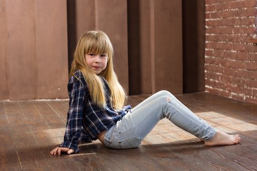 Girl 6 years old in jeans sitting on the floor