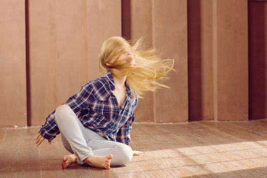 Girl 6 years old in jeans sitting on the floor. Hair fluttering