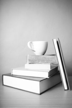 stack of book with coffee cup on wood table background black and white color tone style