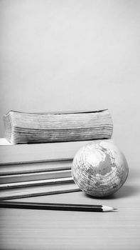 book and earth ball with black pencil on wood background black and white color tone style