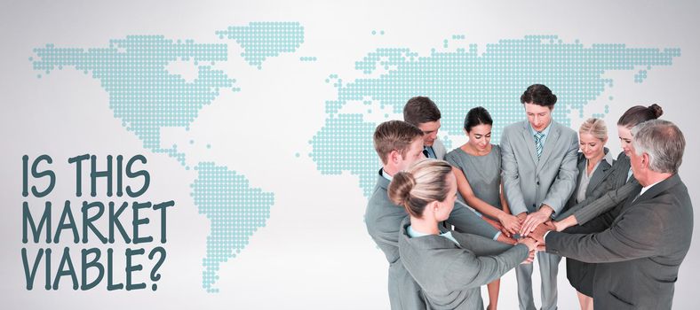 Smiling business team standing in circle hands together against green world map on white background