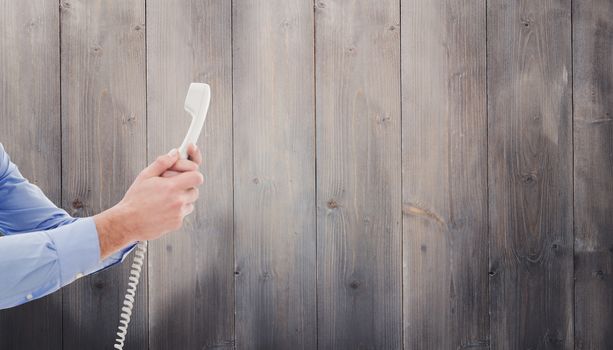 Businessman holding phone against pale grey wooden planks