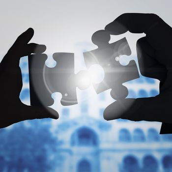 Mid section of a businessman in suit with hands out against jigsaw