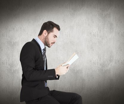 Businessman lying on the floor while reading a book against white and grey background