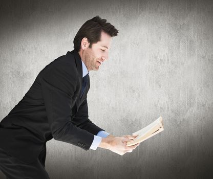 Businessman lying on the floor while reading a book against white and grey background