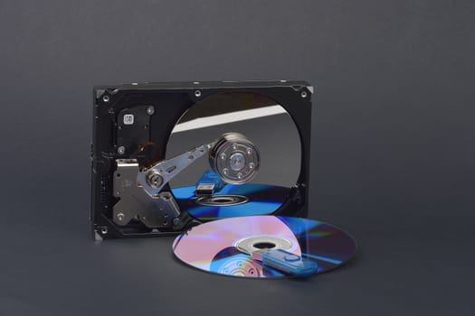 Flash card lying on a disk and a opened hard disk on  dark grey background
