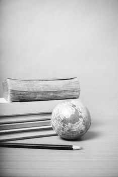 book and earth ball with black pencil on wood background black and white color tone style