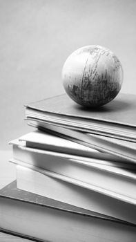 stack of book and earth ball on wood background black and white tone style