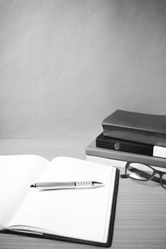 open notebook with stack of book on wood background black and white color tone style