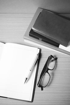 open notebook with stack of book on wood background black and white color tone style