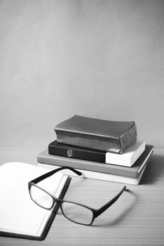 open notebook with stack of book on wood background black and white color tone style