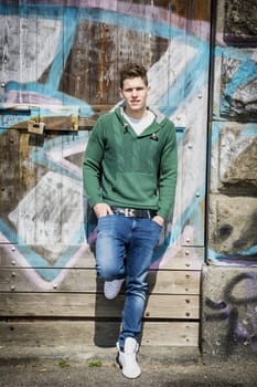 Full body shot of young man standing in front of graffiti