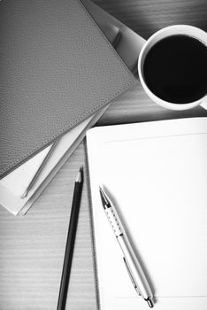 open notebook with book and coffee cup on wood background black and white color tone style