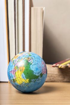 book and earth ball with color pencil on wood background