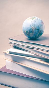 stack of book and earth ball on wood background vintage style