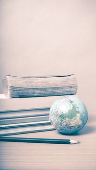 book and earth ball with black pencil on wood background vintage style