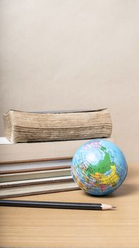 book and earth ball with black pencil on wood background