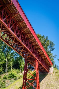 Old red metal bridge in perspective in the summertime