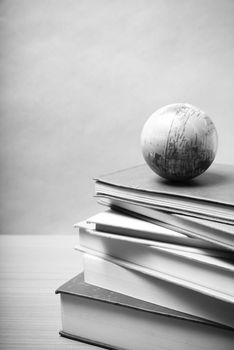 stack of book and earth ball on wood background black and white tone style