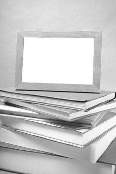 stack of book and photo frame on wood background black and white tone style