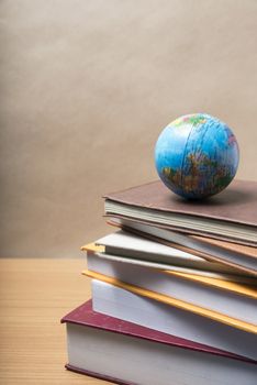 stack of book and earth ball on wood background