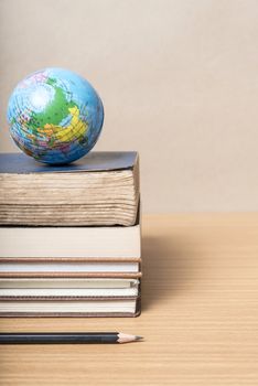 book and earth ball with black pencil on wood background