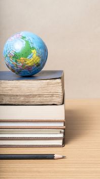 book and earth ball with black pencil on wood background